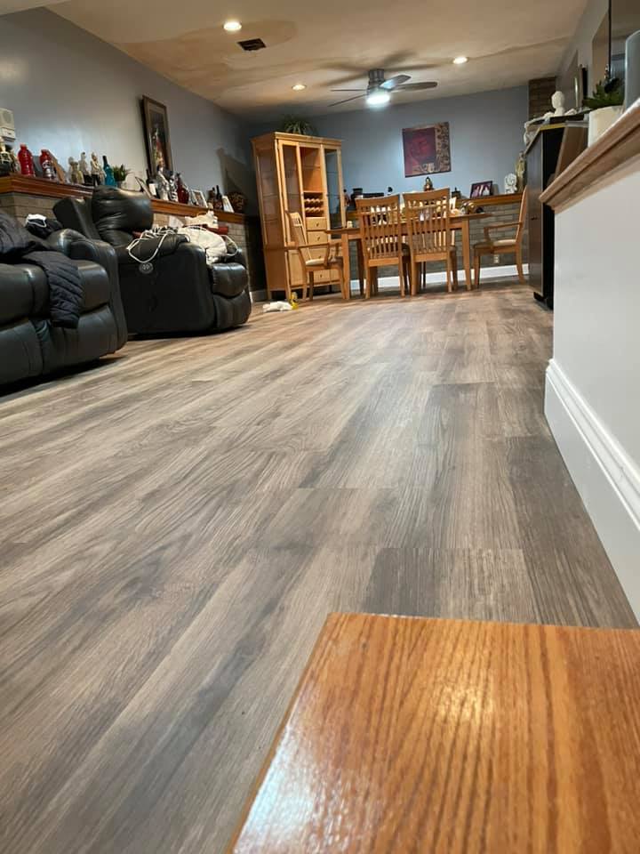 Finished wood like vinyl flooring in gray room with pine dining table and two leather chairs in back ground.
