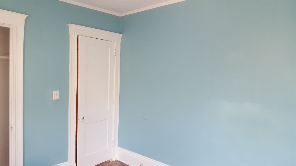 After of yellow wall that is now painted a vibrant blue against white trim work and white door.