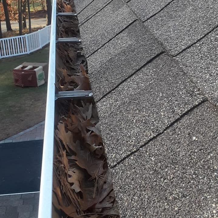Roof view of gutters filled with leaves.