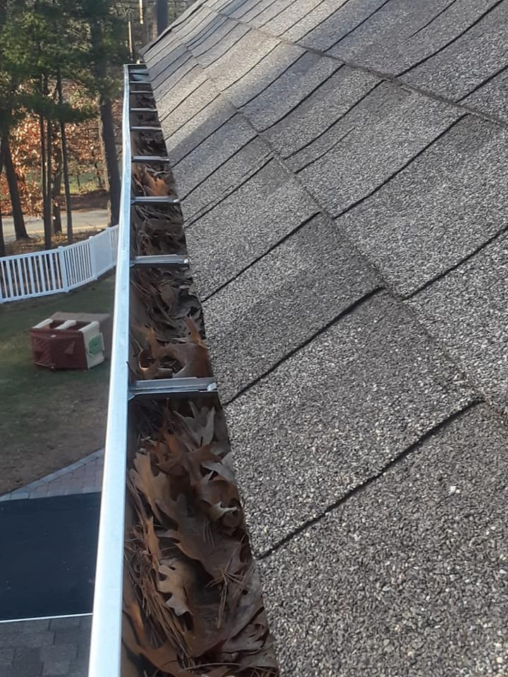 Roof view of gutters filled with leaves.