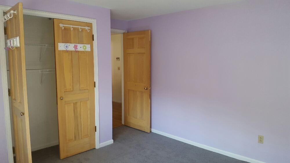 Newly painted purple children's bedroom with white trim and natural bedroom and closet doors.
