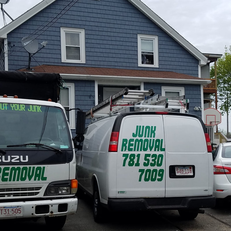 Junk removal truck and work van with junk removal decals and phone number parked in front of the house.