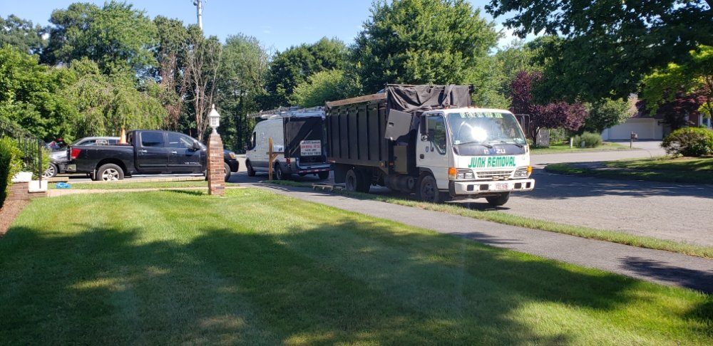 Dun Rite Services junk removal truck and work van on curb in front of house.